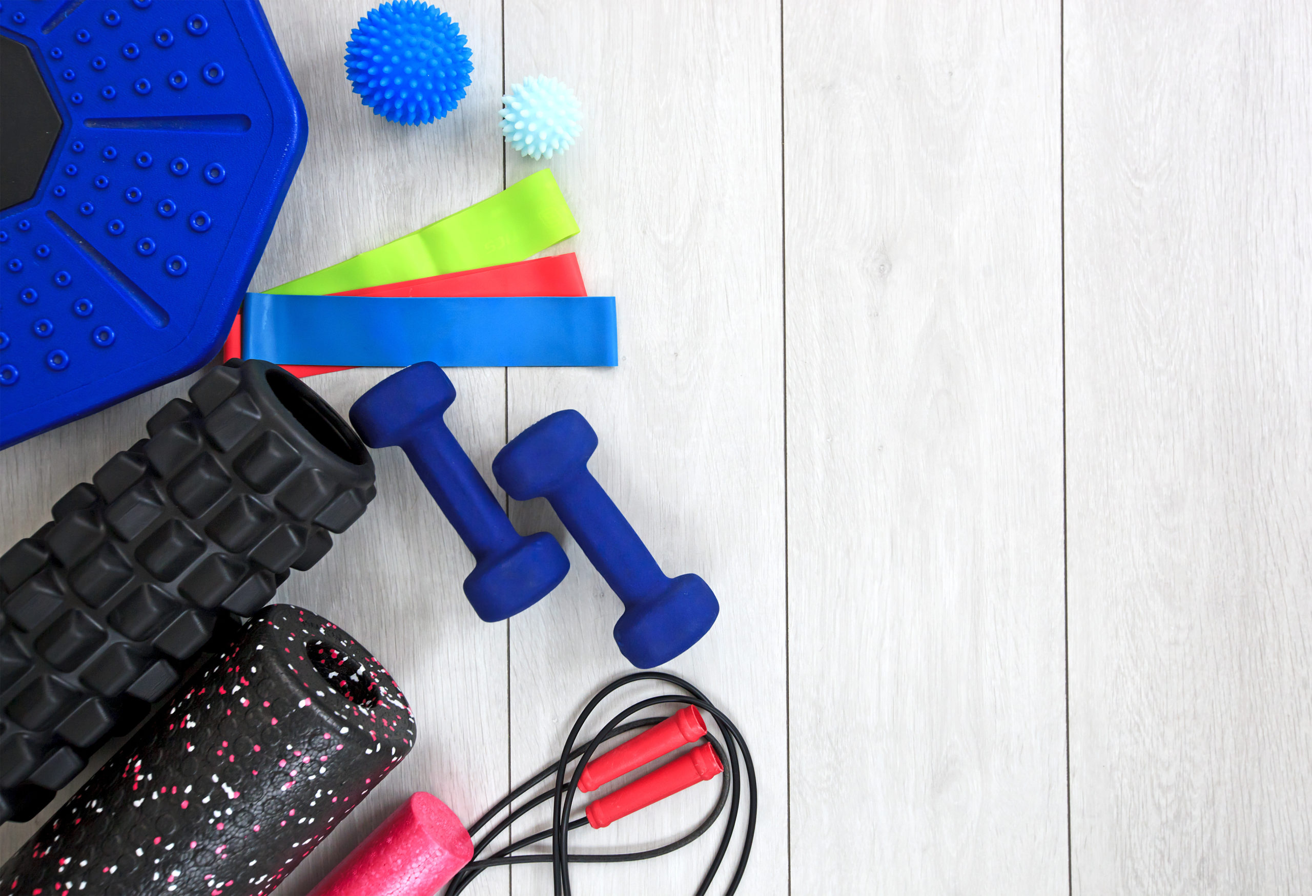 A lot of different fitness and sport accessories and equipment on the wooden floor at home